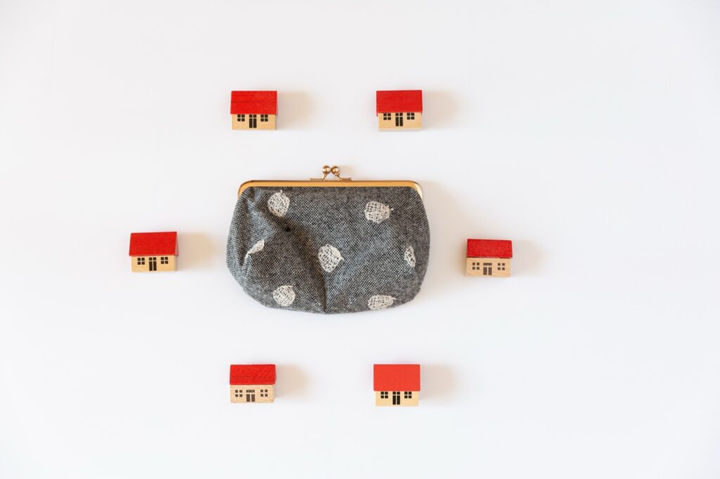 ミニチュアの家に囲まれた財布、お金のイメージ